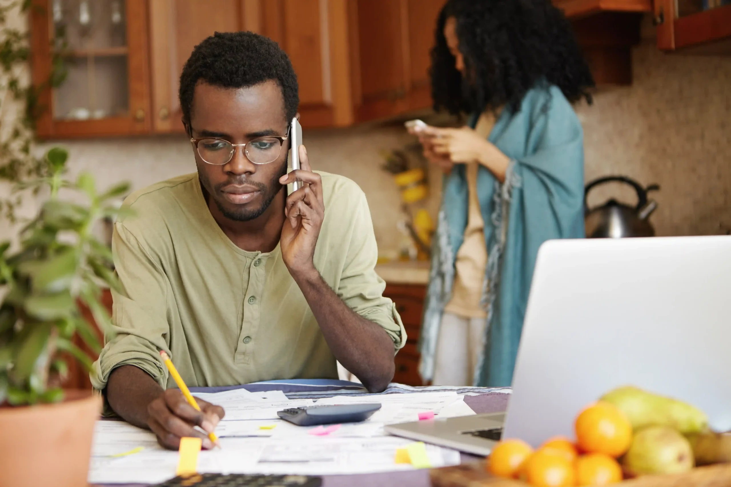 serious-african-man-having-phone-conversation-with-bank-asking-extend-loan-term-paying-out-mortgage-holding-pencil-other-hand-making-notes-documents-lying-table-front-him_compressed